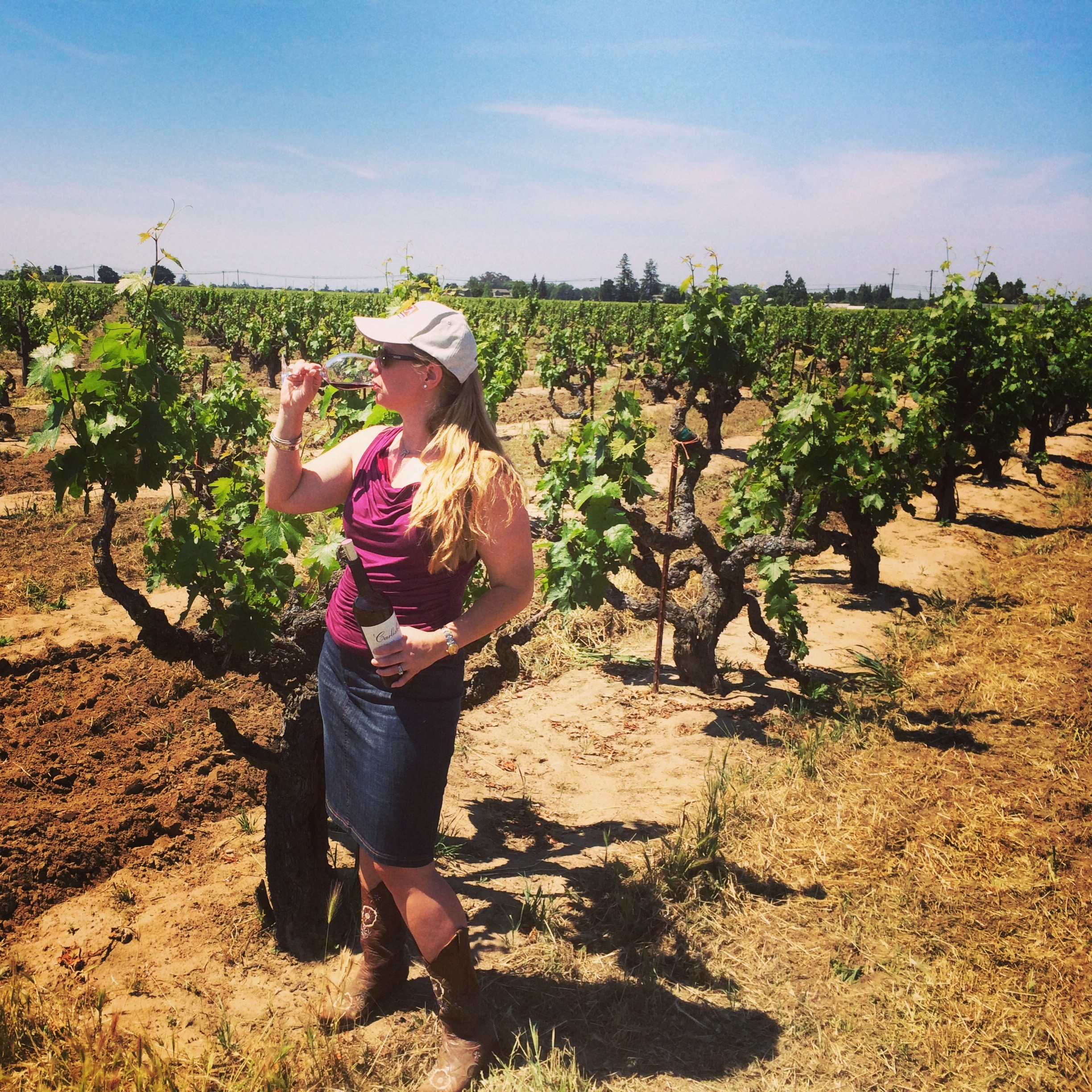 Amy standing in a vineyard with a bottle of wine